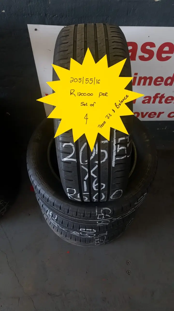 A stack of tyres on the shop floor with a hand-written neon price star showing the size and set price