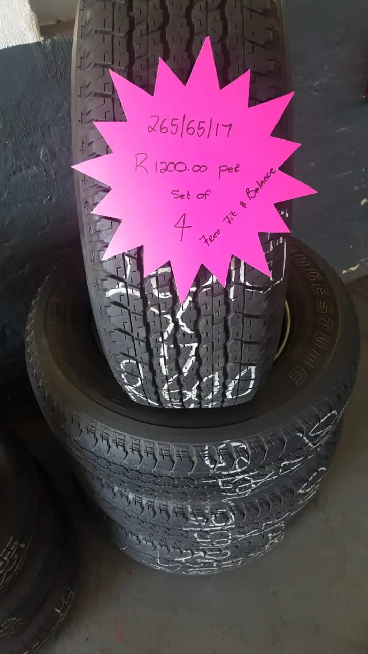 A stack of tyres on the shop floor with a hand-written neon price star showing the size and set price