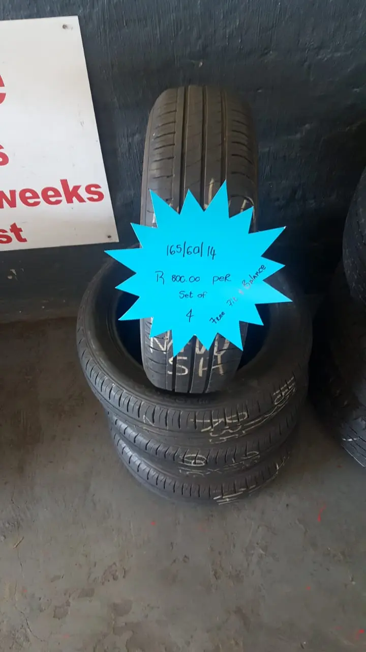 A stack of tyres on the shop floor with a hand-written neon price star showing the size and set price
