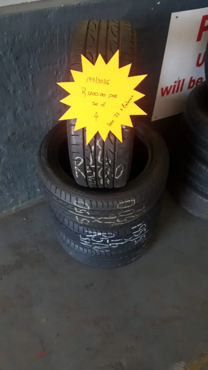 A stack of tyres on the shop floor with a hand-written neon price star showing the size and set price