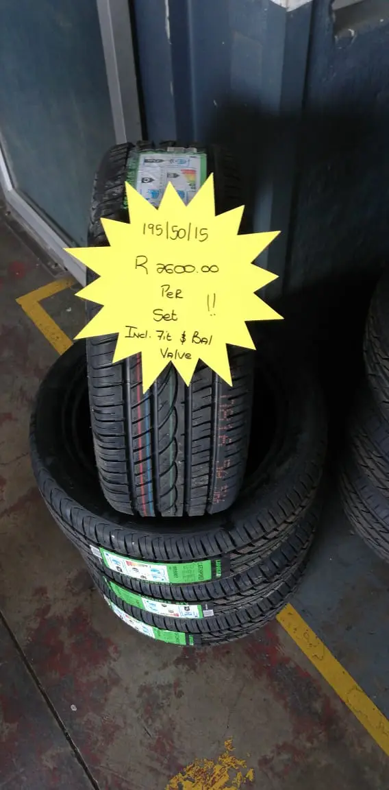 A stack of tyres on the shop floor with a hand-written neon price star showing the size and set price
