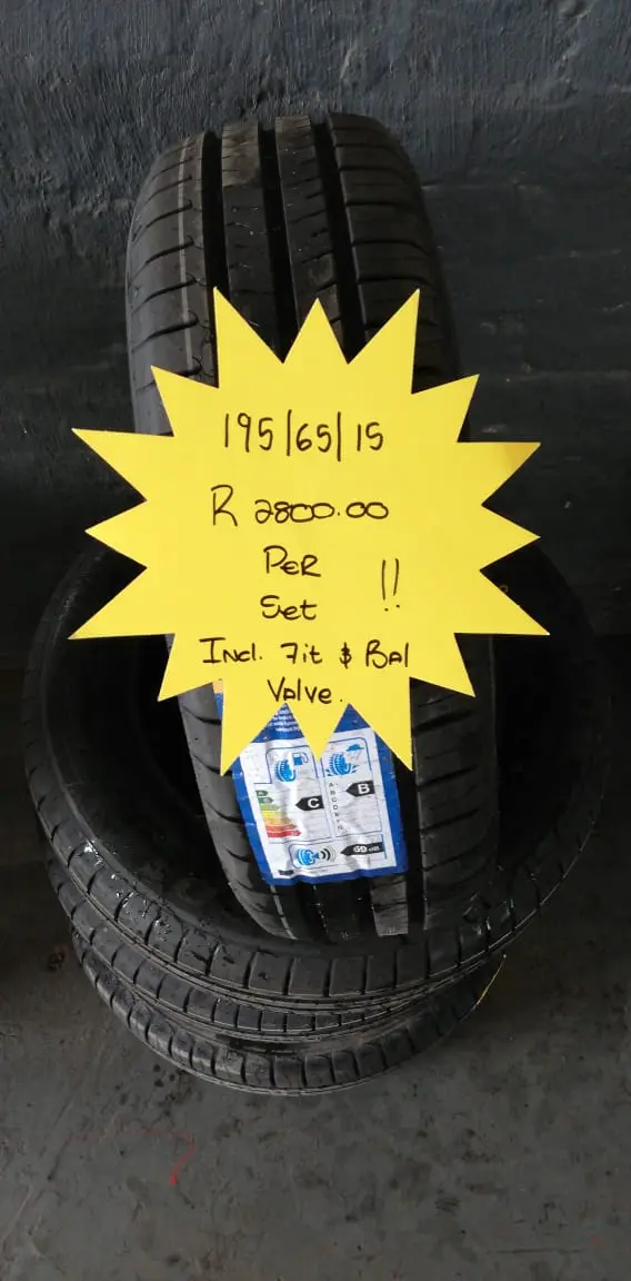 A stack of tyres on the shop floor with a hand-written neon price star showing the size and set price