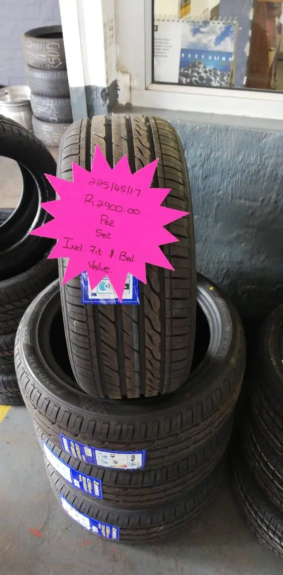 A stack of tyres on the shop floor with a hand-written neon price star showing the size and set price