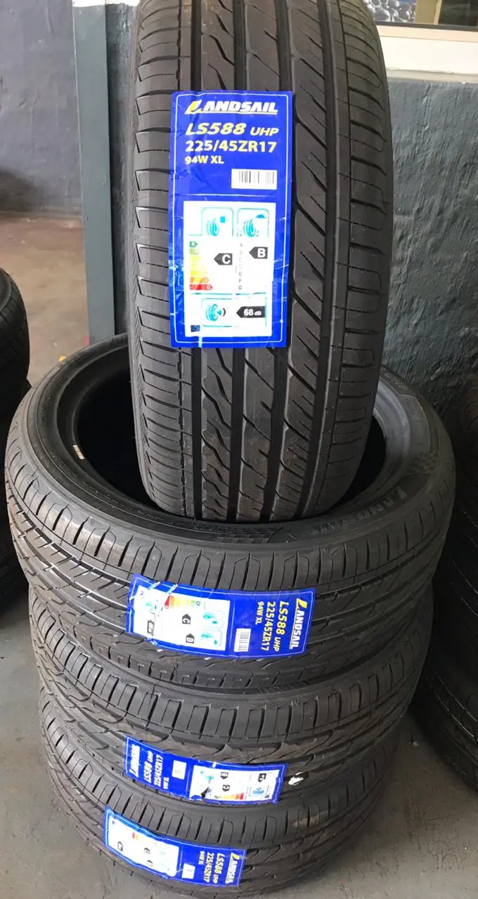 A stack of tyres on the shop floor with a hand-written neon price star showing the size and set price