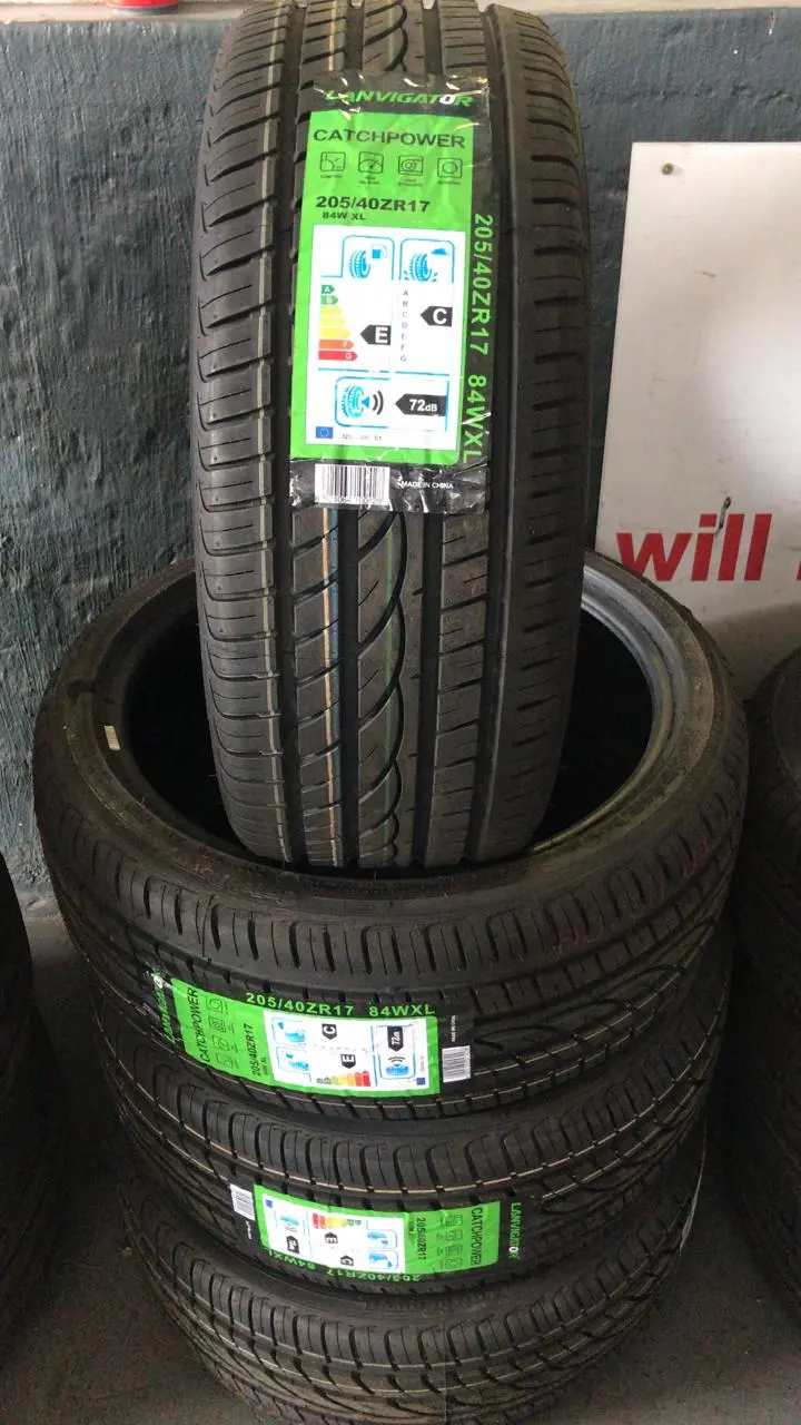 A stack of tyres on the shop floor with a hand-written neon price star showing the size and set price