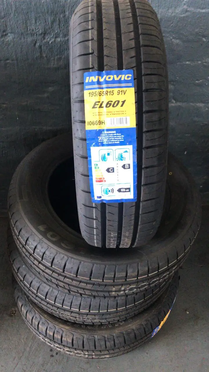 A stack of tyres on the shop floor with a hand-written neon price star showing the size and set price